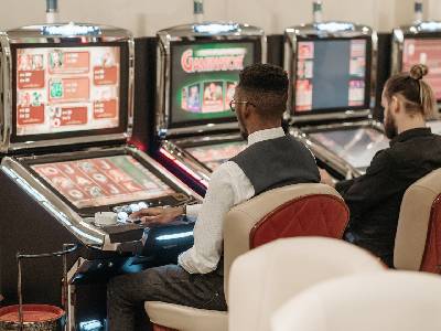 two men playing baccarat at machines